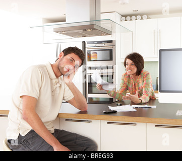 Young Couple Discussing Personal Finances In Modern Kitchen Stock Photo
