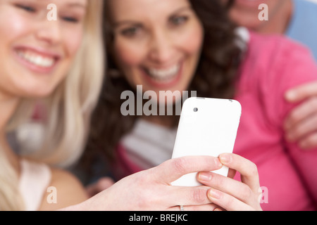 Two Girlfriends Looking At Pictures On Smartphone At Home Stock Photo