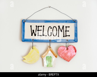Ceramic welcome plate hanging on a nail and wire on a cream wall Stock Photo