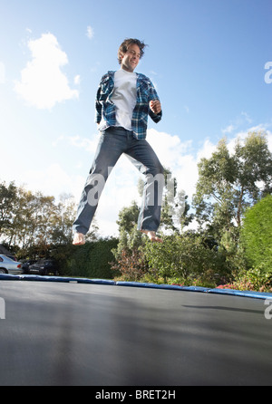 Young Man Jumping On Trampoline Caught In Mid Air Stock Photo