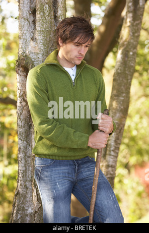 Young Man Outdoors Walking In Autumn Woodland Holding Walking Stick Stock Photo