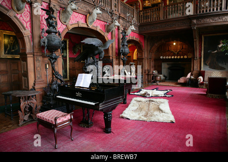 The hall of Kinloch Castle, Rum (Rhum), The Small Isles, Scotland, showing grand piano  and stags' heads on the wall Stock Photo