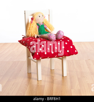Rag doll sitting on red polka dot cushion on childs chair Stock Photo
