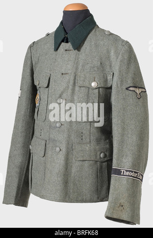 A model 36 tunic,for a member of the 'Theodor Eicke' Regiment. Issue item of field grey,woolen material,the army version with three holes for the belt hooks,dark green collar(moth damage),brown cotton lining stamped with the Munich manufacturer's label and size. Machine-sewn,BeVo version,sleeve eagle. Hand-sewn black sleeve band(BeVo version)with silver grey edging and inscription. Cloth version of the German Cross in Gold on Army fabric. A front-made special badge for tank destruction by an individual soldier(an iron tank silhouette on the back of a,Additional-Rights-Clearences-Not Available Stock Photo