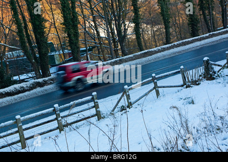Car driving along country road in wintry weather after heavy snow fall Stock Photo