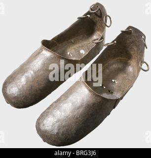A pair of German torture shoes,16th/17th century.Forged iron.Overshoes,made from several pieces of riveted sheet iron.Each has four rings near the heel for fastening the shoe with lacings or leather straps.The bottom plates in each one have three holes with spring-loaded spikes.Length of each 35 cm.Pilloried criminals were forced to wear such shoes to increase their suffering.The delinquent was forced to stand on tiptoe,as otherwise the spikes would penetrate the bottom of his feet,causing severe pain.historic,historical,,17th century,16th centur,Additional-Rights-Clearences-Not Available Stock Photo