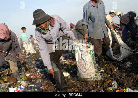 A worker at The Stung Meanchey Landfill in Phnom Penh, Cambodia, takes garbage out of her work boot. Stock Photo