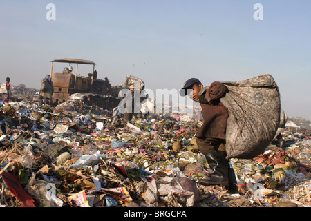 A young child laborer carries a big heavy bag of garbage while working at The Stung Meanchey Landfill in Phnom Penh, Cambodia. Stock Photo