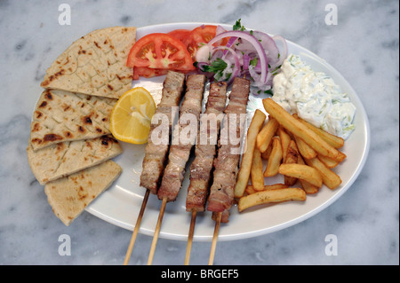 Greek Souvlaki. Pork Skewer on a Plate with Potatoes and Tzatziki, Geece. Stock Photo