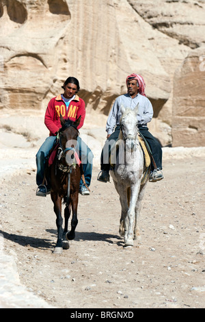 Tourist on horseback riding at the Siq, canyon entrance to the ancient rock carved city Petra, Jordan. Stock Photo