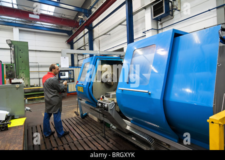 An older worker in the metal industry with CNC milling machine. Stock Photo