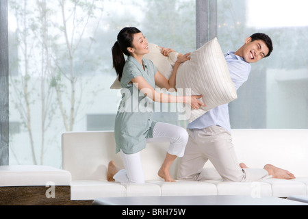 A couple pillow fights in their living room Stock Photo