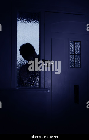 Silhouette of a man peeping through frosted glaas next to front door Stock Photo