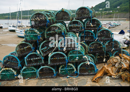 Lobster and crab pots stacked on harbour wall in the coastal resort of New Quay, Ceredigion, West Wales, UK Stock Photo