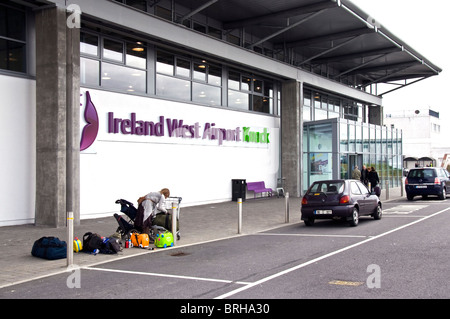 Entrance to Ireland West Airport Knock Airport A woman loads bags onto a trolley Stock Photo