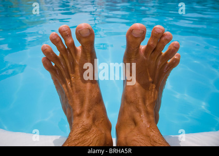 A man's feet by a blue pool Stock Photo