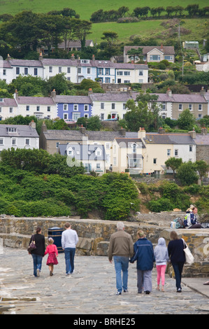 People walking along harbour terraced cottages on hillside overlooking the Welsh seaside holiday resort of New Quay Ceredigion Stock Photo