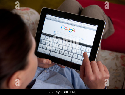 Woman searching internet using Google search engine on an iPad tablet ...