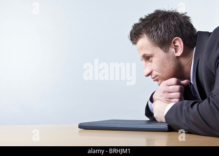 Businessman Leaning on Desk Looking Thoughtful Stock Photo