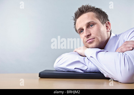 Businessman Leaning on Desk Looking Thoughtful Stock Photo