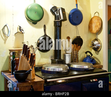 A corner of an English country style kitchen with an Aga or range and pots and pans and cooking utensils Stock Photo