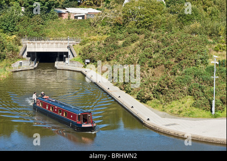 Canal boat has emerged from Falkirk Wheel through the tunnel and turning to enter the first Union Canal lock further right Stock Photo