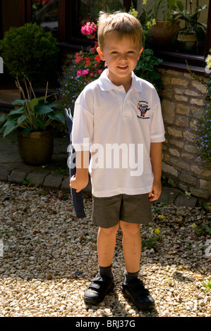 Young boy wearing school uniform carrying a satchel on his shoulder ...