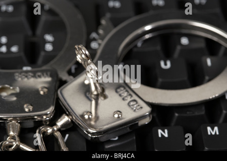 key inserted in handcuffs on a computer keyboard Stock Photo