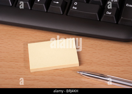 yellow post-it notes and pen on desk in front of a computer keyboard Stock Photo