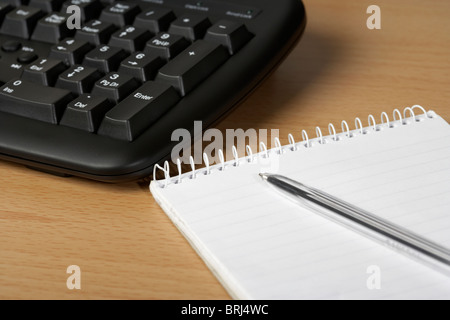 notepad and pen on desk in front of a computer keyboard Stock Photo