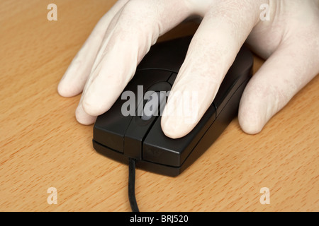 hand wearing surgical rubber glove on a computer mouse protecting against infection or security concept Stock Photo