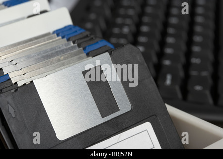 box of old floppy storage disks in front of a computer keyboard Stock Photo