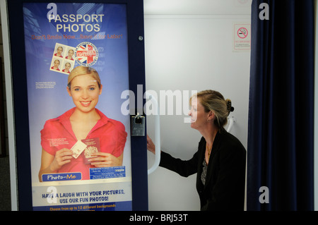 Photo booth woman preparing to have passport picture taken using public portrait machine Stock Photo