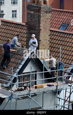 Builders replacing ridge tiles on roof refurbishment, UK Stock Photo