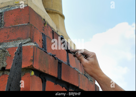 Builder re-pointing brick chimney stack Stock Photo