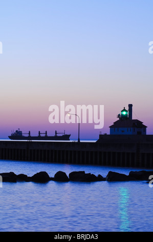 A ship awaits entry into Duluth Harbor outside of the canal breakwater at dawn in Duluth, Minnesota. Stock Photo