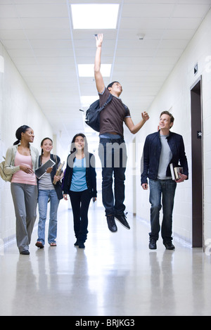High school students in school corridor watching friend jumping Stock Photo