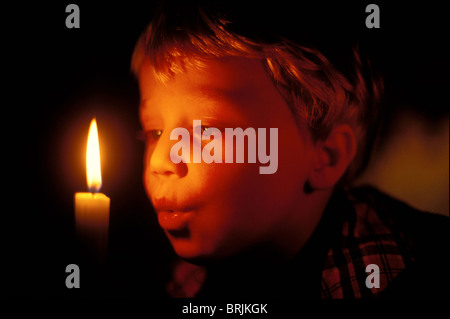 eight-year old boy blowing out his birthday candle Stock Photo