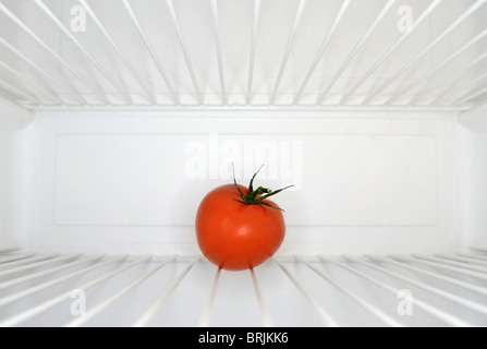 Single red tomato sitting on shelf inside refrigerator Stock Photo