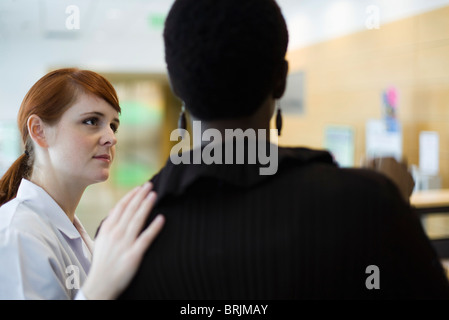 Female healthcare worker putting hand on patient's shoulder Stock Photo