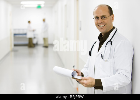 Doctor leaning against wall, portrait Stock Photo