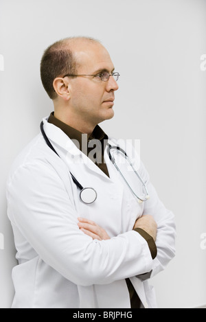 Doctor leaning against wall, arms folded, portrait Stock Photo