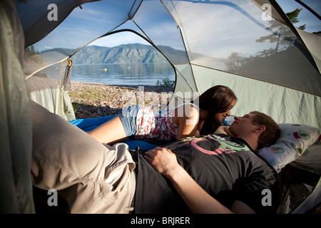 A young couple camping talk in their tent next to a lake in Idaho. Stock Photo