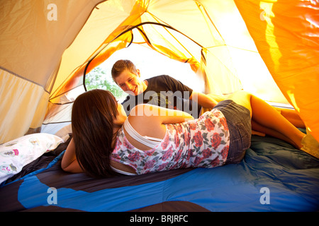 A young couple camping talk in their tent next to a lake in Idaho. Stock Photo