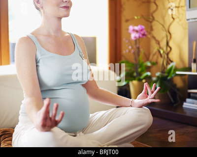 Pregnant woman relax doing yoga, sitting in lotus position over white background Stock Photo 