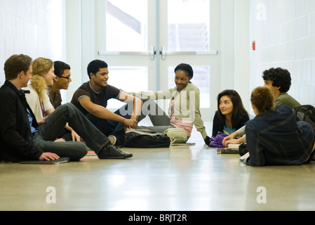Students hanging out together, sitting on school corridor floor Stock Photo