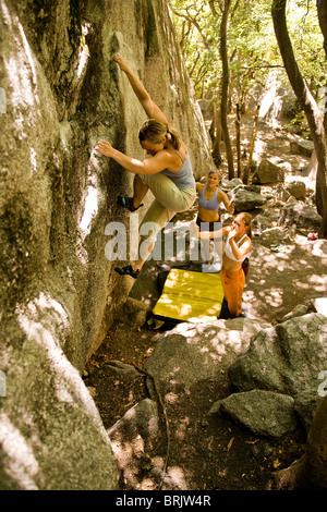 Protected by her friends spotting below, a woman boulders in Utah's Wasatch Mountains.