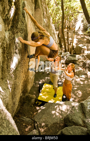 Protected by her friends spotting below, a woman boulders in Utah's Wasatch Mountains.