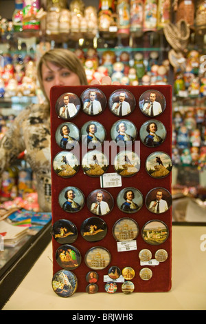 Shop assistant holding a display of badges of Peter the Great and Putin St Petersburg Russia Stock Photo