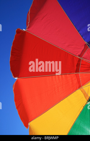 part of a rainbow beach umbrella with blue sky background Stock Photo